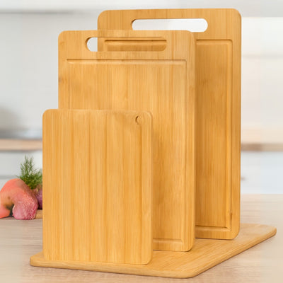 Set of three bamboo cutting boards on a wooden surface with a blurred background