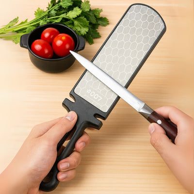 Person sharpening a knife on a whetstone with tomatoes and herbs in the background