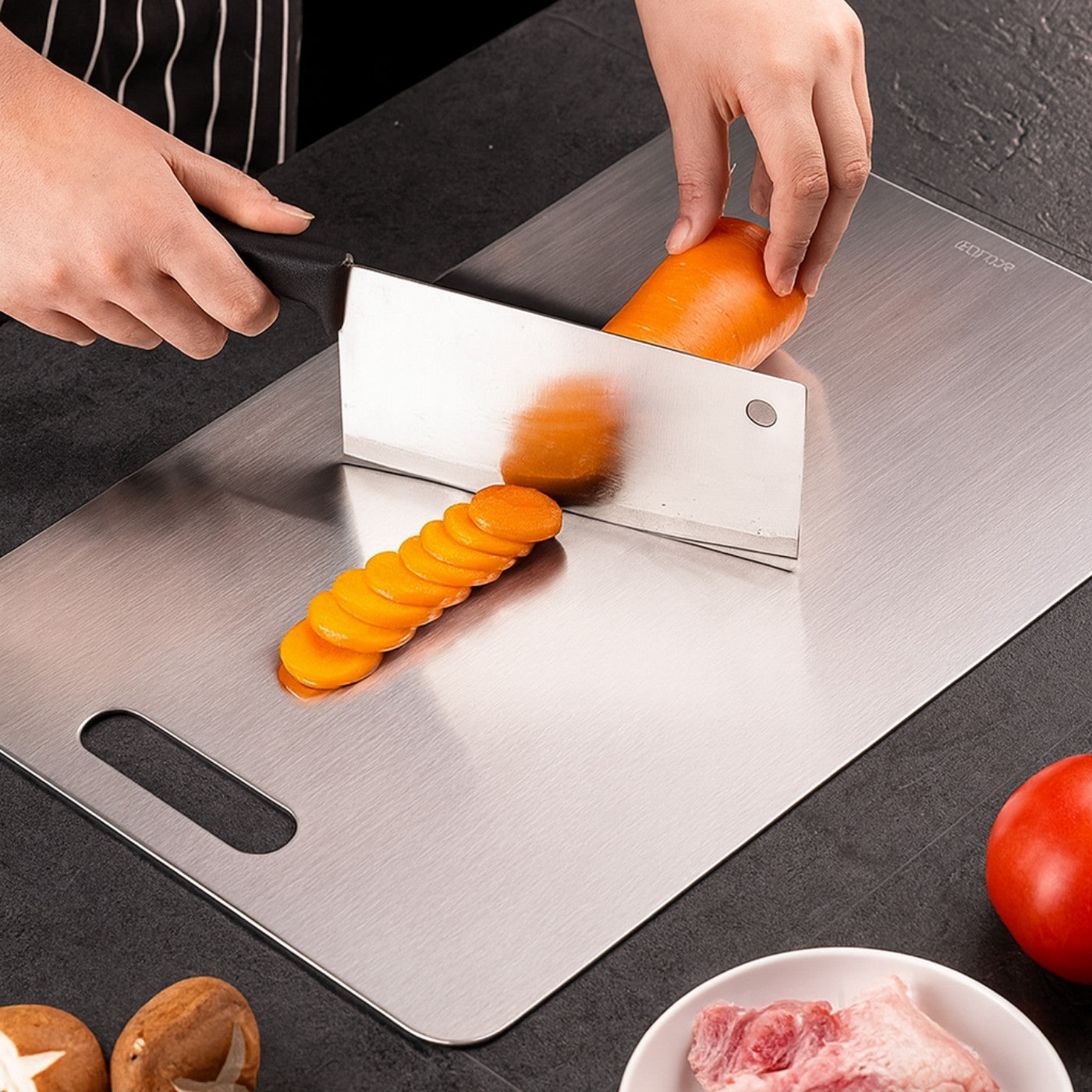 Person slicing an onion on a metal cutting board with a knife.