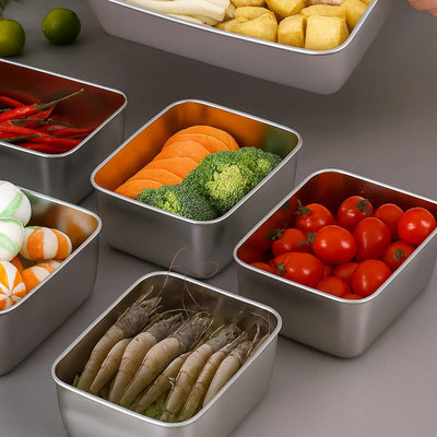 Set of metal containers with various food items including vegetables and seafood on a gray surface.