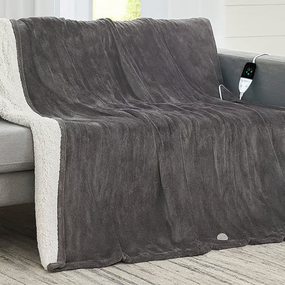 Gray electric blanket draped over a sofa with a power cord visible.