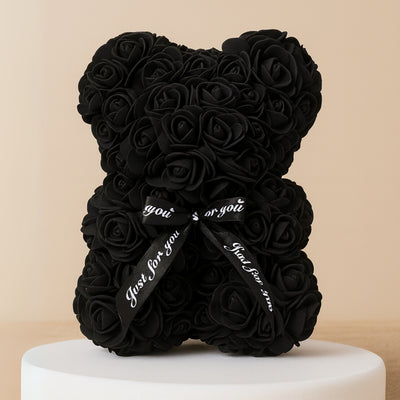 Black rose teddy bear with a ribbon on a beige background