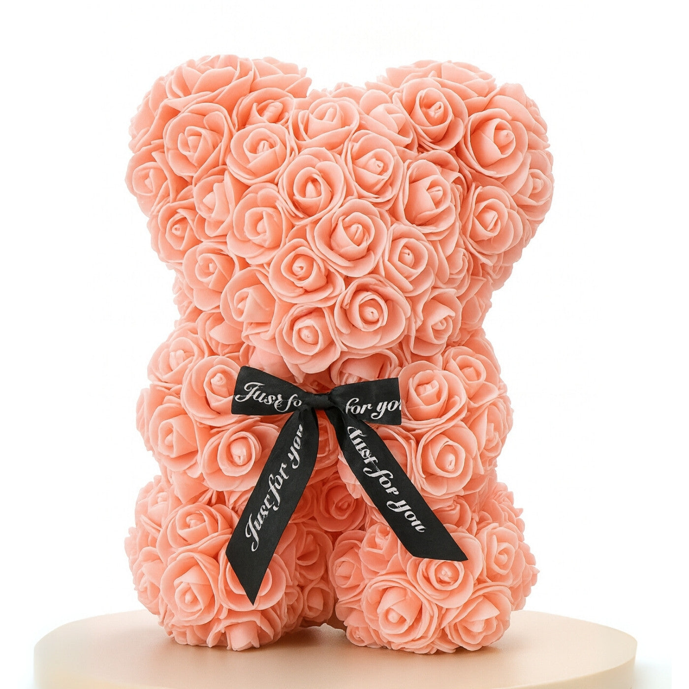 Pink rose teddy bear with a black ribbon on a white background