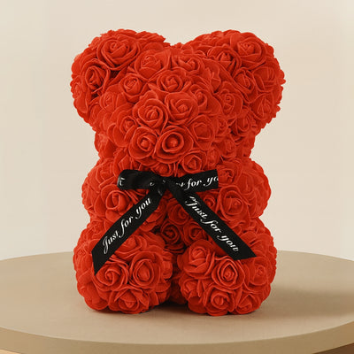 Red rose teddy bear with a black ribbon on a beige background